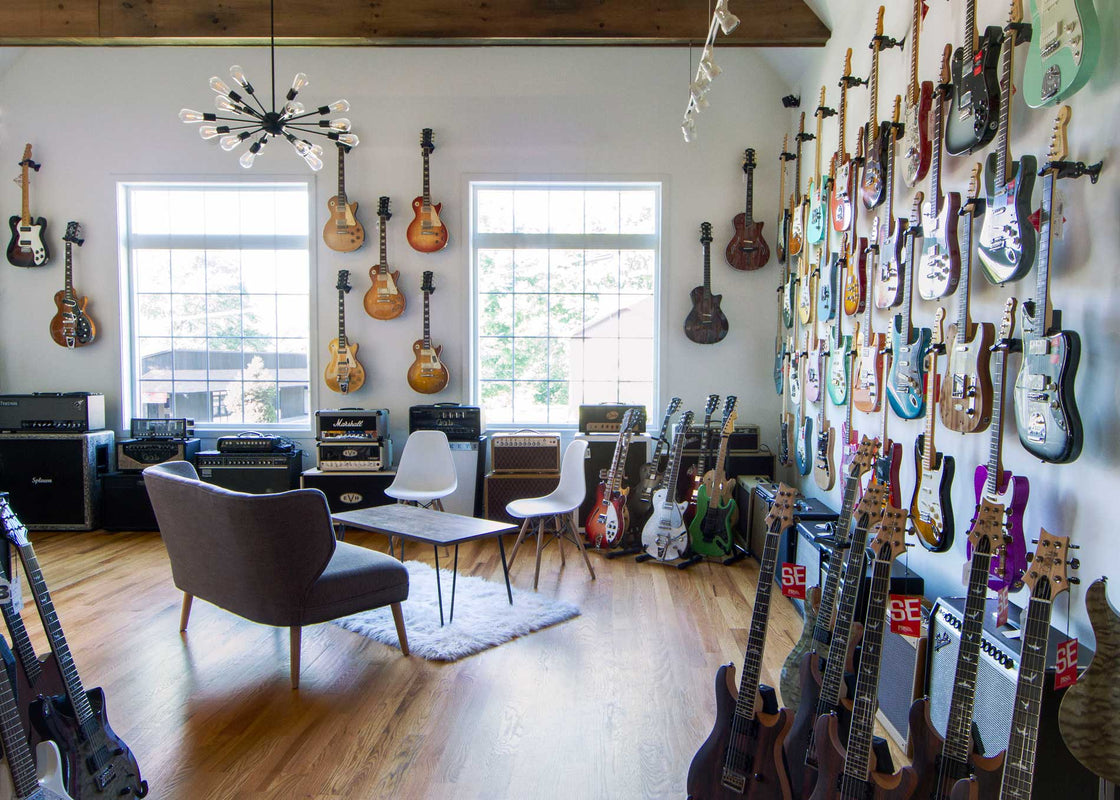 The Brian's Guitars showroom, featuring electric guitars lining the walls and floor, and a seating area in the center.